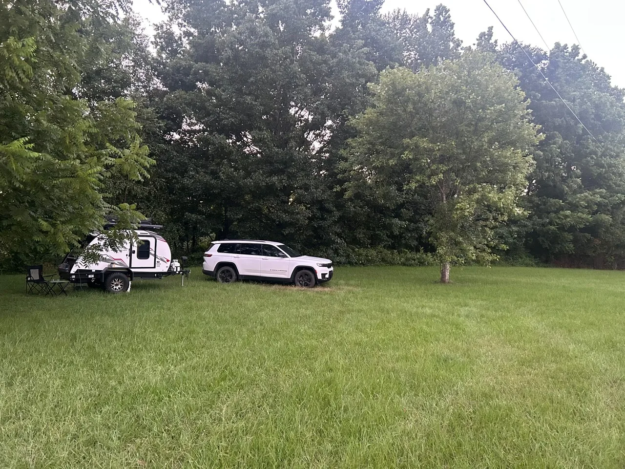 Camper and SUV parked in the open meadow at the campground
